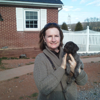 Woman holding black lab puppy